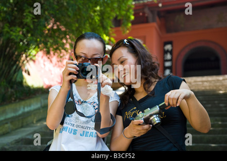 Deux jeunes femmes chinoises voir photo sur appareil photo numérique en face de l'entrée de Grand Bouddha Leshan Dafo Sichuan Chine JMH3229 Banque D'Images