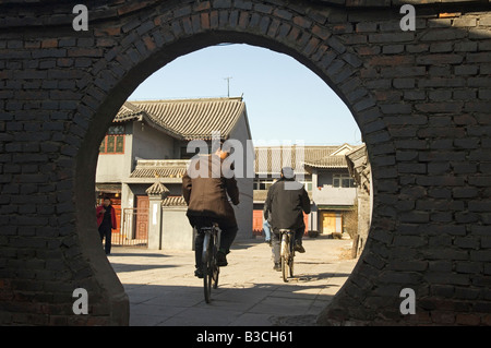 La Chine, Beijing. Studio de cinéma Beiputuo temple et de définir l'emplacement, deux cyclistes équitation à travers une entrée voûtée. Banque D'Images