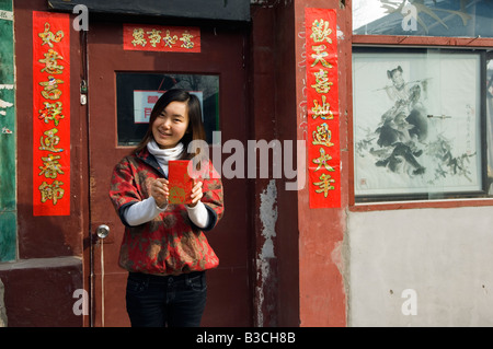 La Chine, Beijing. Une jeune Chinoise portant des vêtements de style chinois traditionnel tenant une enveloppe Hongbao qui est reçu avec de l'argent par les étudiants et les enfants pendant le Nouvel An Chinois Fête du Printemps (MR). Banque D'Images