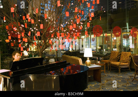 La Chine, Beijing. Un pianiste jouant dans un hall de l'hôtel décorées pendant le Nouvel An chinois. Banque D'Images