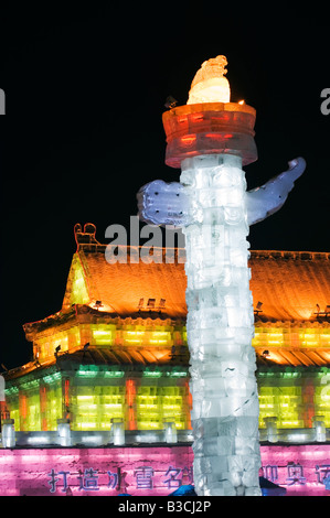 La Chine, le nord-est de la Chine, Heilongjiang Province, ville de Harbin. Festival de lanternes de glace. Une sculpture de glace colorée réplique de la Cité Interdite's Huabiao statue et porte de la paix céleste à Beijing est éclairée la nuit. Banque D'Images