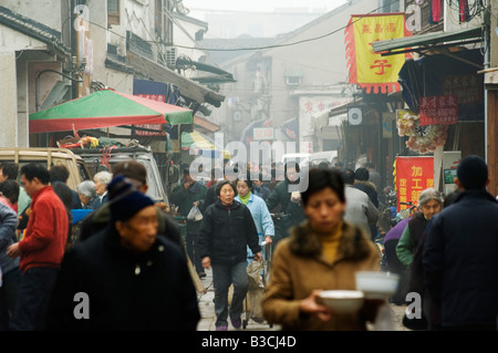 La Chine, la province de Jiangsu, Suzhou City. Une femme portant des bols de nouilles dans une rue animée Banque D'Images