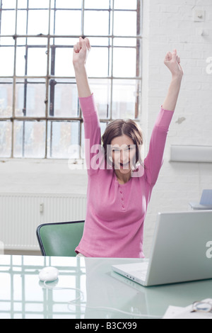 Young businesswoman in office, cheering Banque D'Images