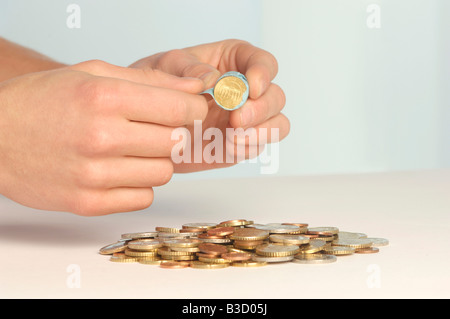 Hand holding coin roll, close-up Banque D'Images