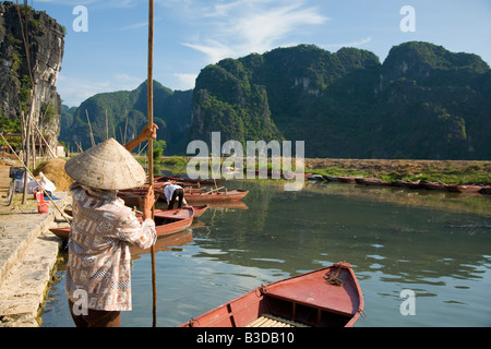 Dame vietnamienne prépare à punt voyageurs descendent la rivière à Tam Coc près de Ninh Binh Banque D'Images