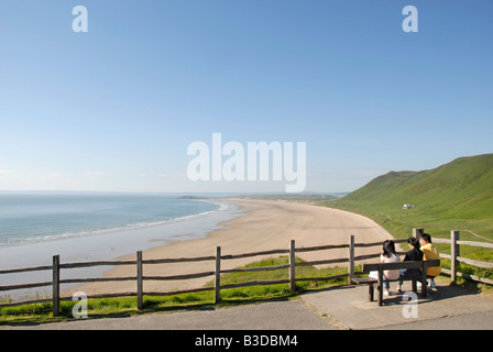 Groupe assis sur un banc, vue sur plage et mer, Rhossili Beach, péninsule de Gower, au Pays de Galles, en Grande-Bretagne, en Europe Banque D'Images