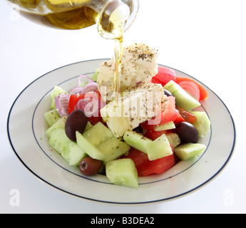 On verse de l'huile d'olive sur une salade grecque traditionnelle Banque D'Images