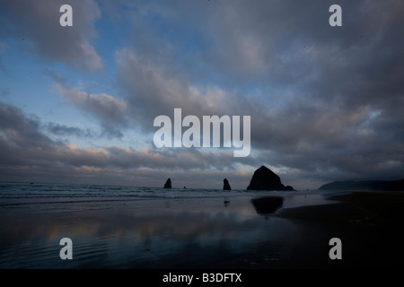 Lever du soleil et les piles de la mer sur la plage de Cannon Oregon avec un ciel dramatique dans l'arrière-plan Banque D'Images