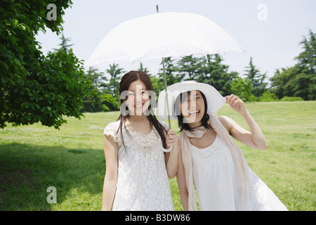 Young women smiling and holding umbrella Banque D'Images