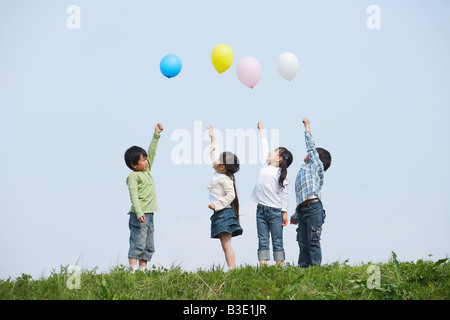 Enfants holding colorful balloons in park Banque D'Images