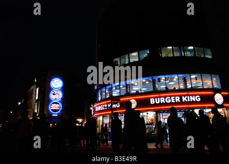 Les gens qui passent le restaurant Burger King à Leicester Square at night London England Banque D'Images