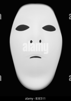 Un masque de visage humain lumineux blanc sur fond noir Banque D'Images