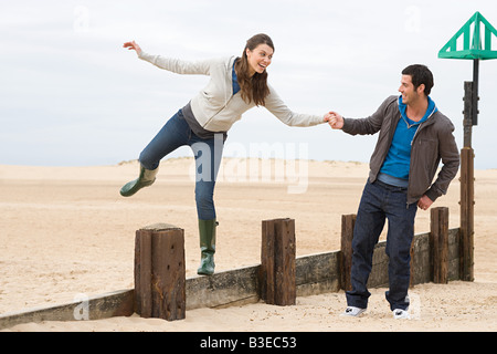 Couple playing sur clôture en bois at beach Banque D'Images