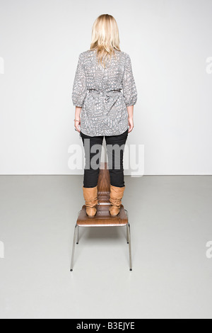 Femme debout sur une chaise Banque D'Images