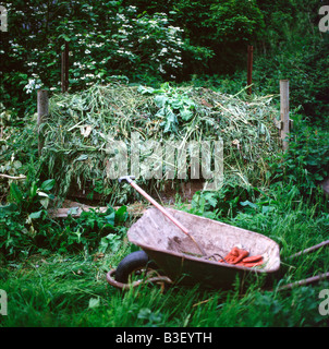 Compost de gazon, brouette, fourchette et des gants de jardinage dans un jardin Brecon au Pays de Galles UK KATHY DEWITT Banque D'Images