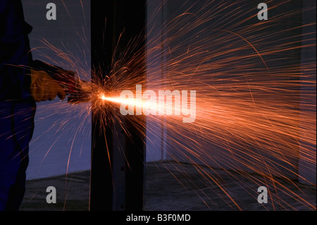 Des étincelles d'une meuleuse d'angle qu'elle coupe à travers une poutre d'acier Banque D'Images