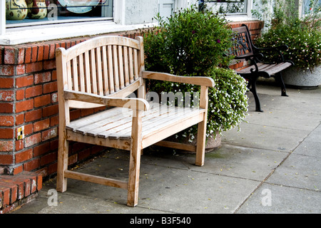 Banc en bois en face d'un mur de briques par un trottoir à côté d'un buisson à Half Moon Bay, Californie Banque D'Images