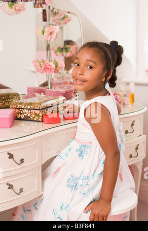 Jeune fille assise à miroir dans chambre smiling Banque D'Images