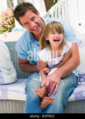 L'homme et de la jeune fille assise sur patio laughing Banque D'Images