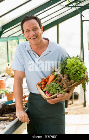 L'homme dans les émissions de holding panier de légumes smiling Banque D'Images