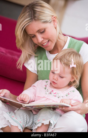 Mère dans la salle de séjour lecture livre avec baby smiling Banque D'Images