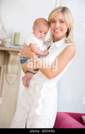 Mère dans la salle de séjour holding baby smiling Banque D'Images
