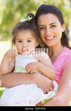 Mother holding daughter outdoors smiling Banque D'Images