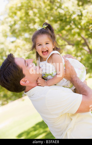 Père holding daughter outdoors smiling Banque D'Images