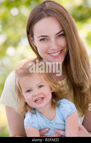 Mother holding daughter outdoors smiling Banque D'Images