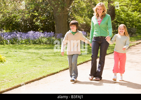 Mère et deux jeunes enfants marchant sur la main chemin smiling Banque D'Images