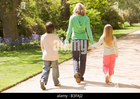 Mère et deux jeunes enfants marchant sur la main chemin smiling Banque D'Images