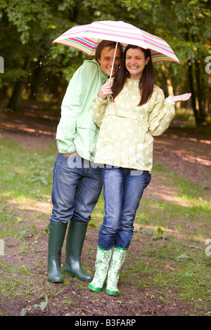 Couple dans la pluie avec umbrella smiling Banque D'Images