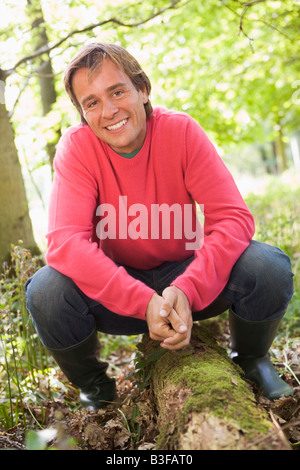 L'homme à l'extérieur en bois assis sur log smiling Banque D'Images