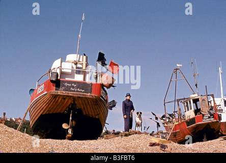 La pêche dans HASTINGS UN HOMME promène son chien sur HASTINGS PLAGE ENTRE BATEAUX DE PÊCHE COMMERCIALE 1995 Banque D'Images