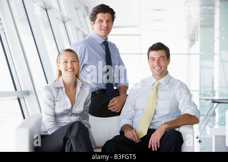 Trois businesspeople sitting smiling in office lobby Banque D'Images