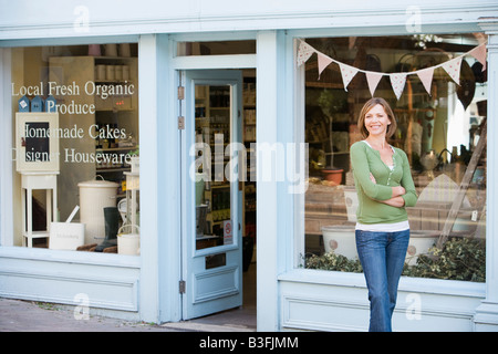 Woman standing in front of organic food store smiling Banque D'Images