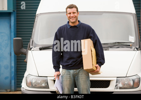 Deliveryperson standing avec van holding clipboard et fort smiling Banque D'Images