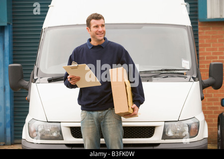 Deliveryperson standing avec van holding clipboard et fort smiling Banque D'Images