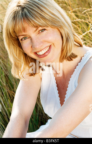 Woman sitting outdoors smiling Banque D'Images