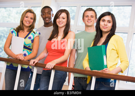 Cinq étudiants dans couloir leaning on railing with notebooks Banque D'Images