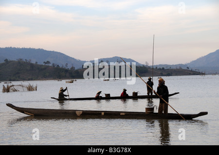 Les pêcheurs vietnamiens en canots traditionnels sillhouetted au coucher du soleil le lac Lak Vietnam Banque D'Images