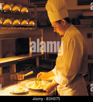 Vue latérale d'un chef de garnir la nourriture dans une cuisine de restaurant de l'hôtel Banque D'Images