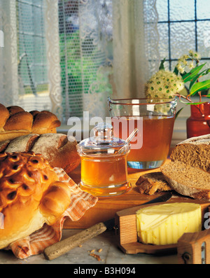 Still Life of Honey pot avec du pain frais et du beurre sur table de cuisine par fenêtre. Banque D'Images