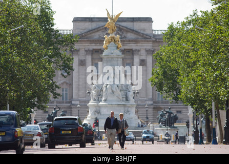 Un couple marche dans le centre de la Mall loin de l'Édifice commémoratif Victoria et l'imprimeur de la palais de Buckingham à Londres Banque D'Images