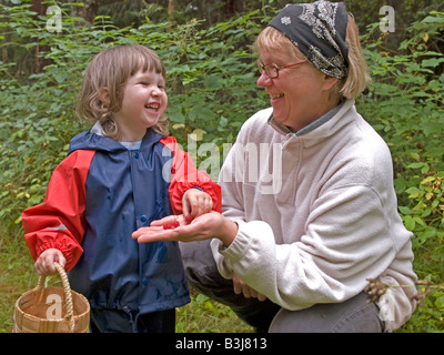 Femme d'âge moyen avec un petit enfant dans l'âge de 3 ans s'amuser par cueillette en forêt les framboises sucrées manger Banque D'Images