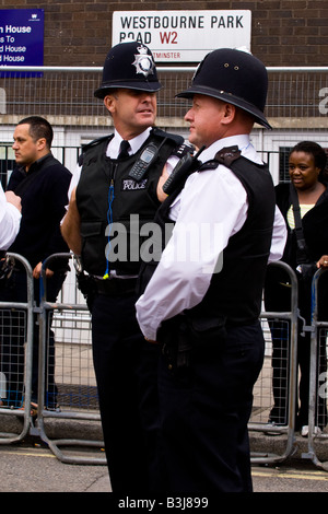 Notting Hill Carnival Parade deux agents de la Police métropolitaine en uniforme , chat et de plaisanter tout en regardant les spectateurs et participants Banque D'Images