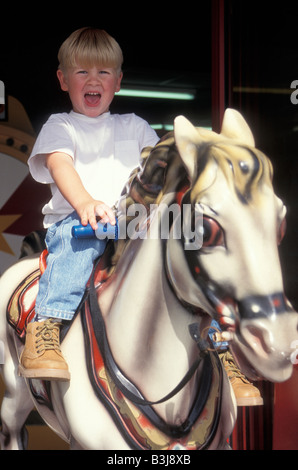 Petit garçon sur tour sur cheval en jeux électroniques Banque D'Images