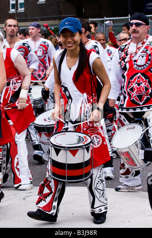 Défilé du carnaval de Notting Hill , rire les jeunes adolescentes tambour oriental fille joue dans le célèbre fanfare brésilienne Batala Banque D'Images