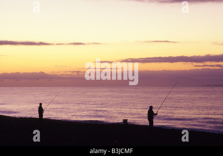 2 Deux silhouettes de personnes de pêche surf au lever du soleil sur la plage dans l'Ouest, Misquamicut Rhode Island USA. Banque D'Images