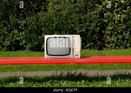 Téléviseur portable style rétro rouge sur le banc de parc Banque D'Images